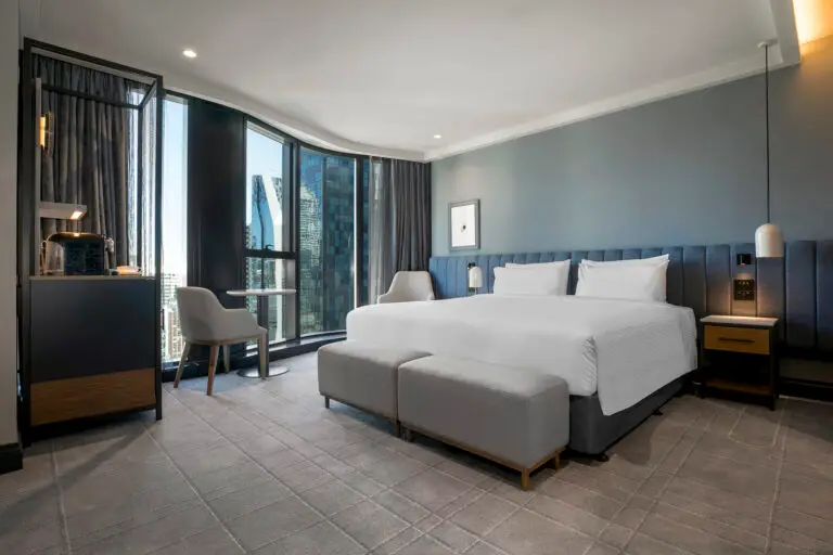 Guest room with a king bed, upholstered bench, window seating and floor-to-ceiling city views