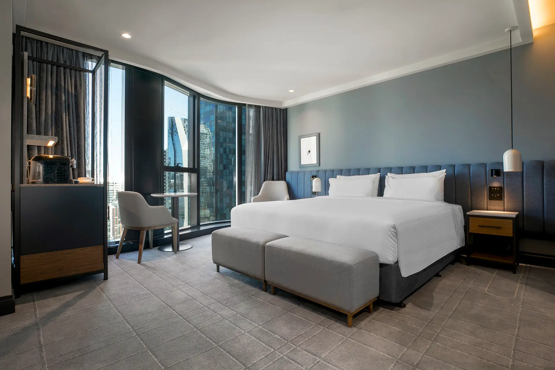 Guest room with a king bed, upholstered bench, window seating and floor-to-ceiling city views