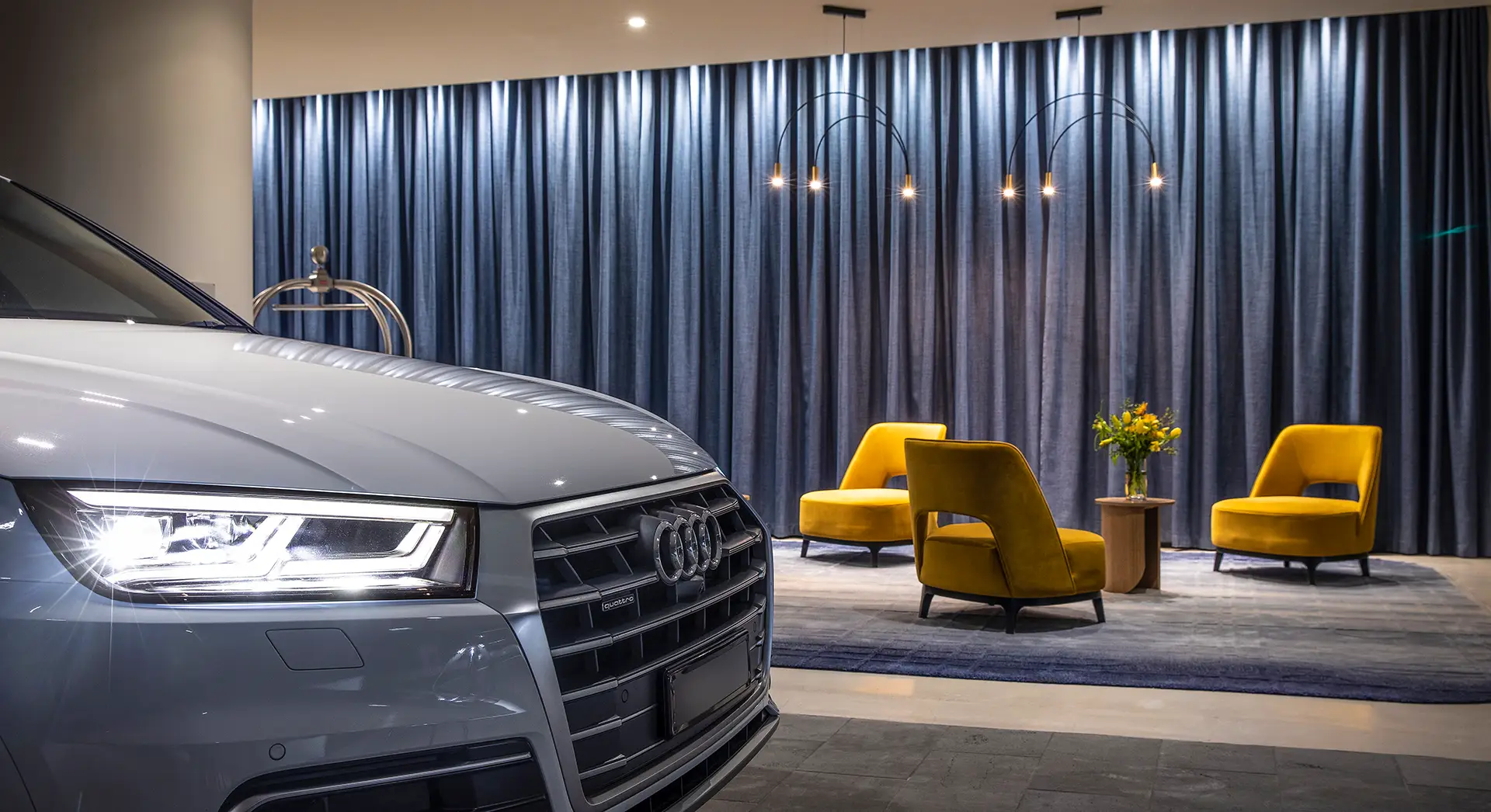 Grey Audi at the hotel arrival area with yellow lounge chairs and blue curtains