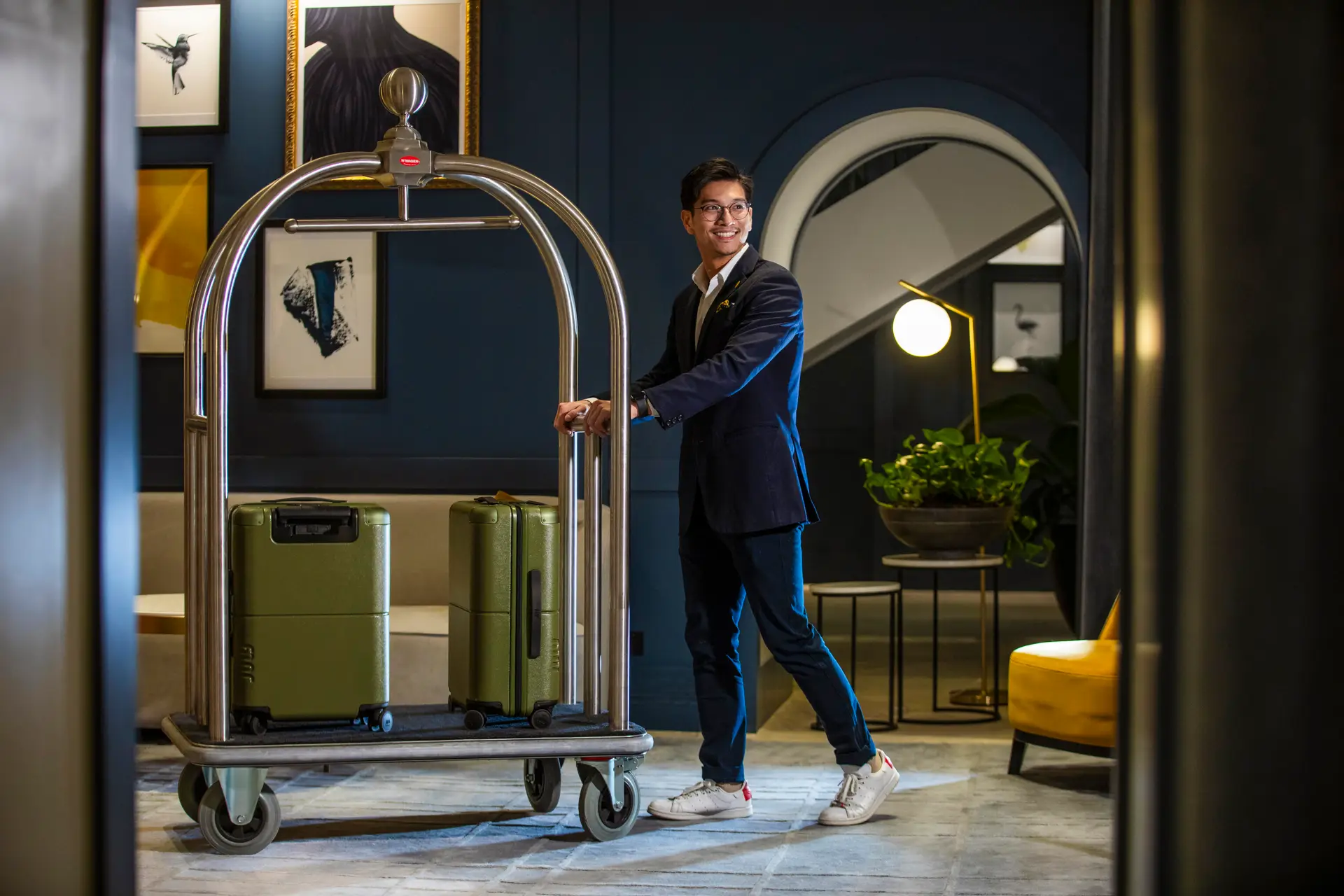 A hotel porter wheeling guests' luggage through the lobby