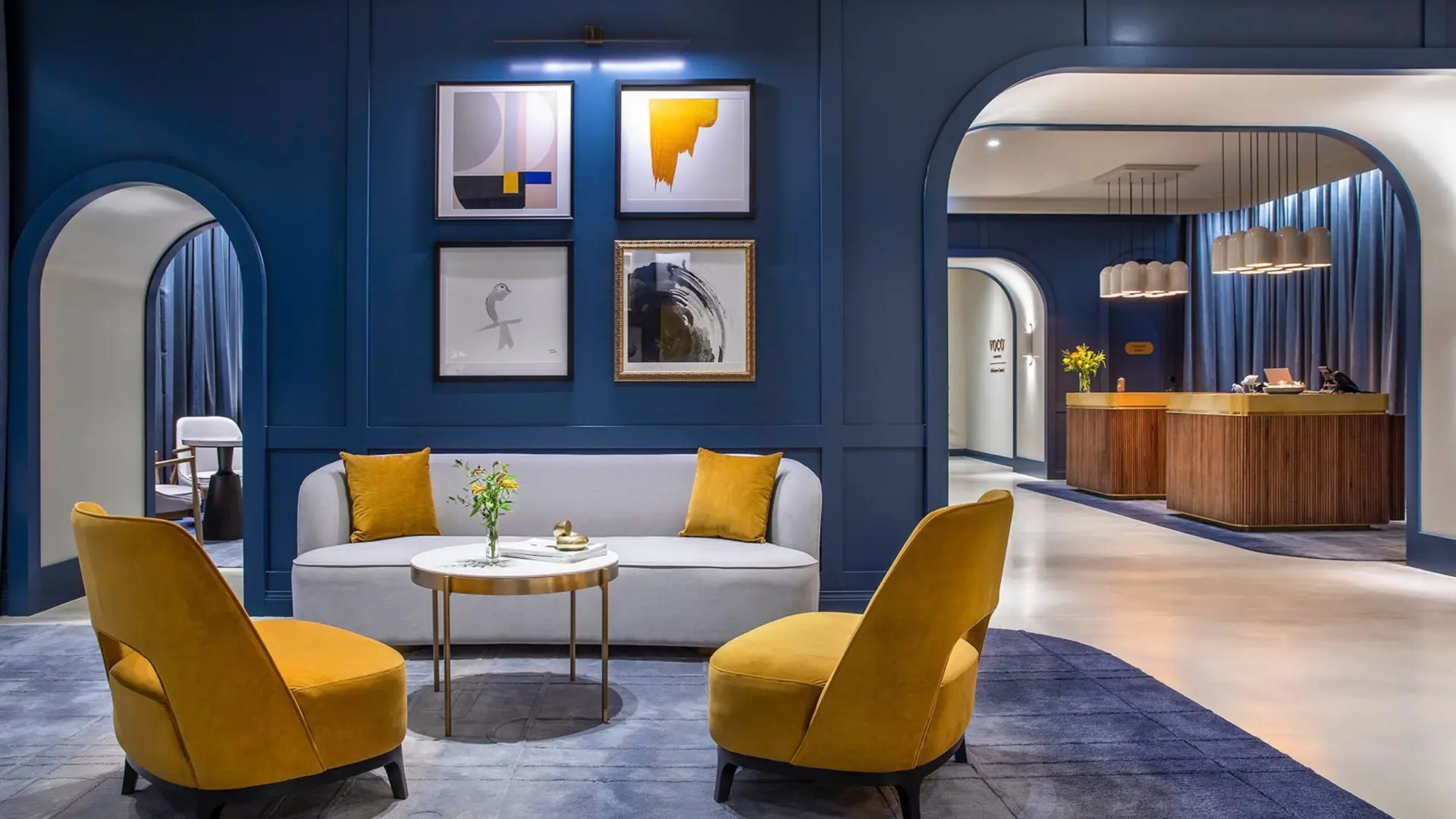 Lobby seating with mustard armchairs, blue walls and an arched view towards reception