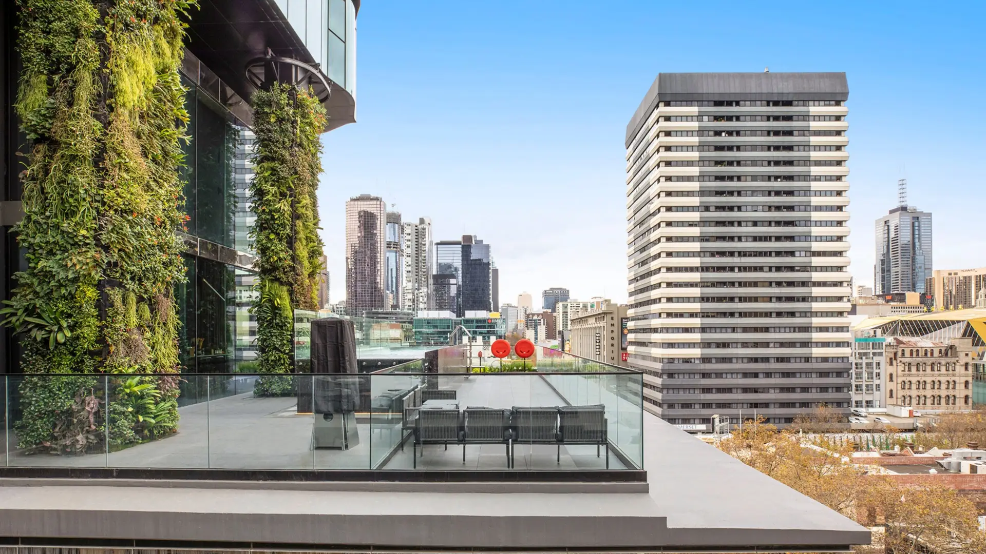 Outdoor terrace with vertical greenery, glass balustrade and views across Melbourne buildings