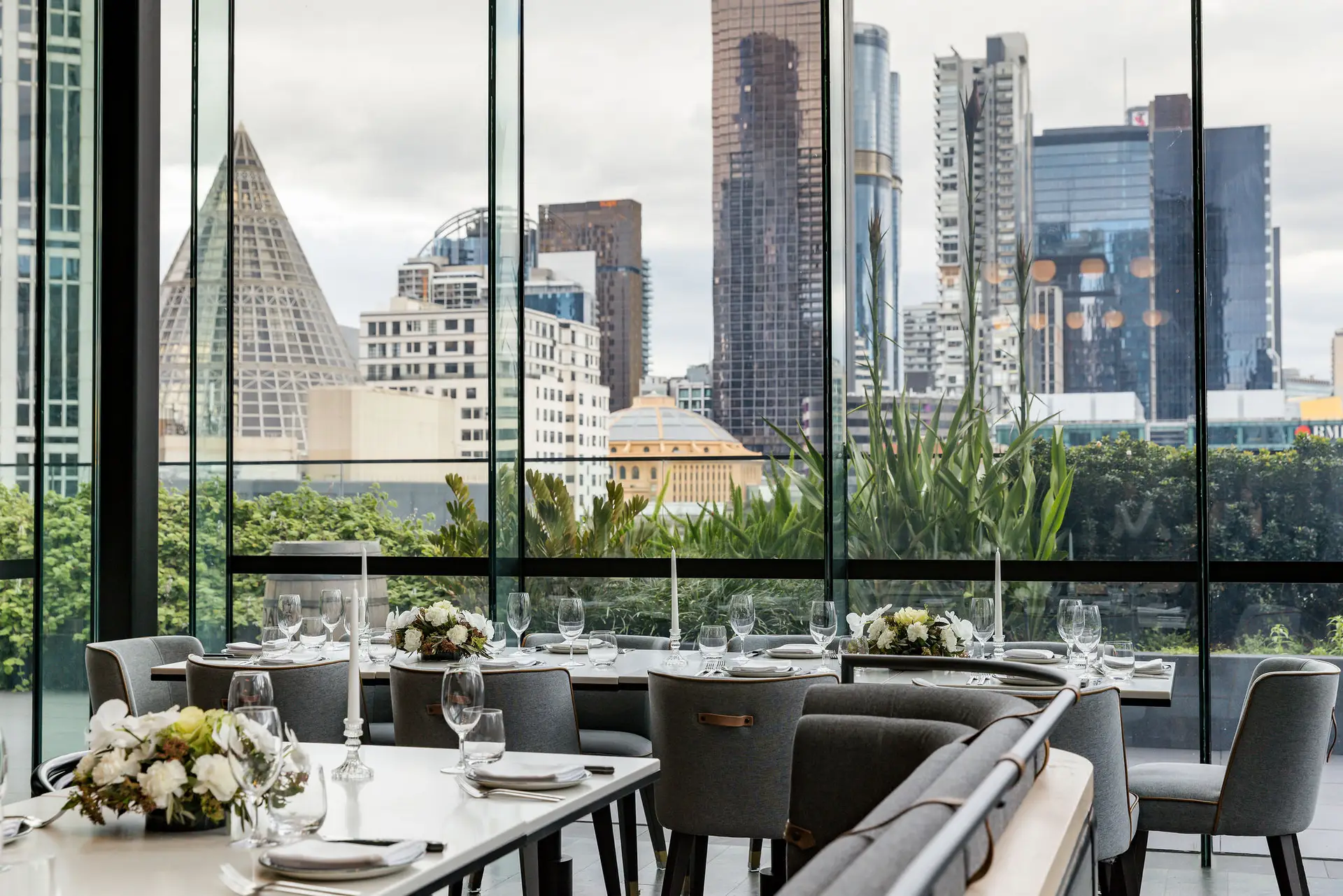 A private dining room set for a group, with windows over the Melbourne skyline