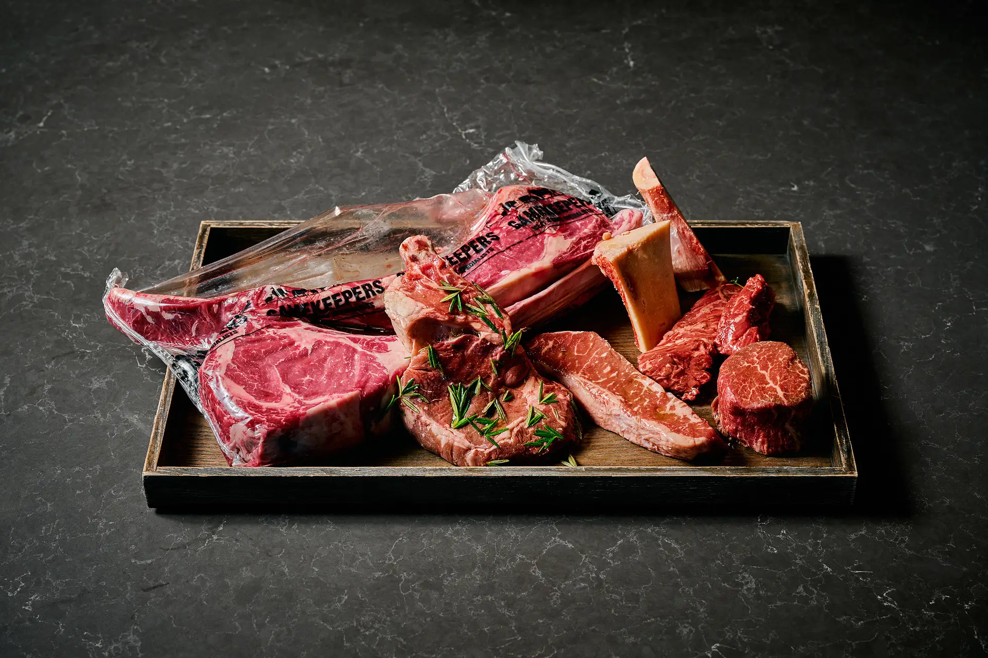 Assortment of premium raw meats arranged on a wooden tray