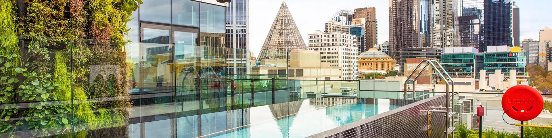 Rooftop pool beside a vertical garden with views across central Melbourne
