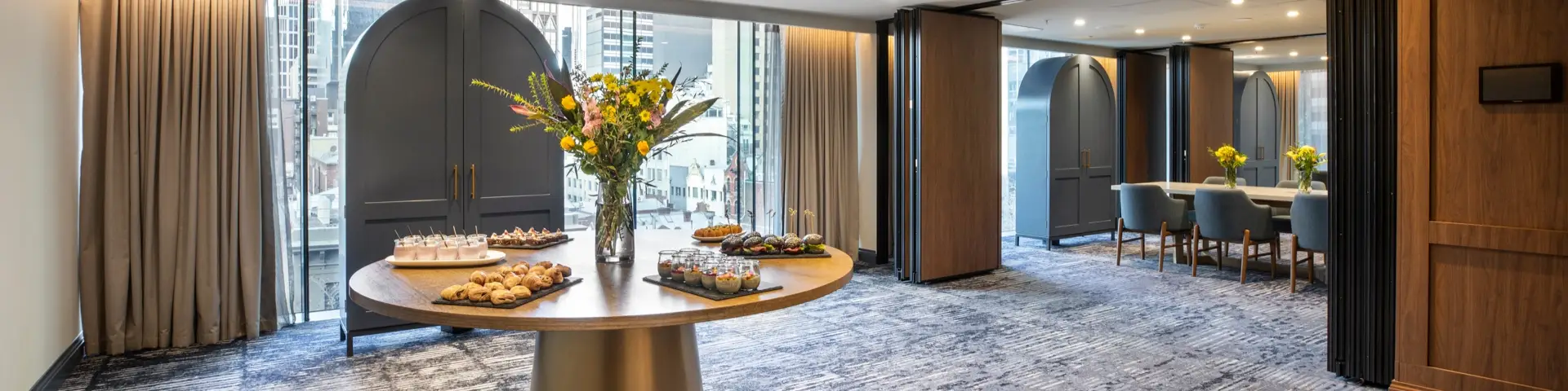 Event dining space with long tables, candles, floral centrepieces and large windows