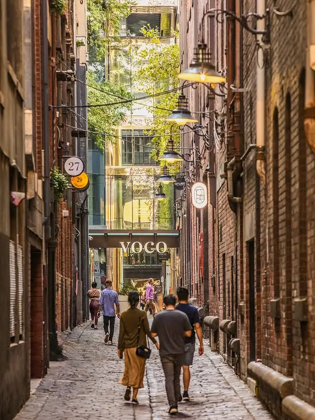 Pedestrians walking along a narrow brick laneway towards the voco Melbourne Central entrance
